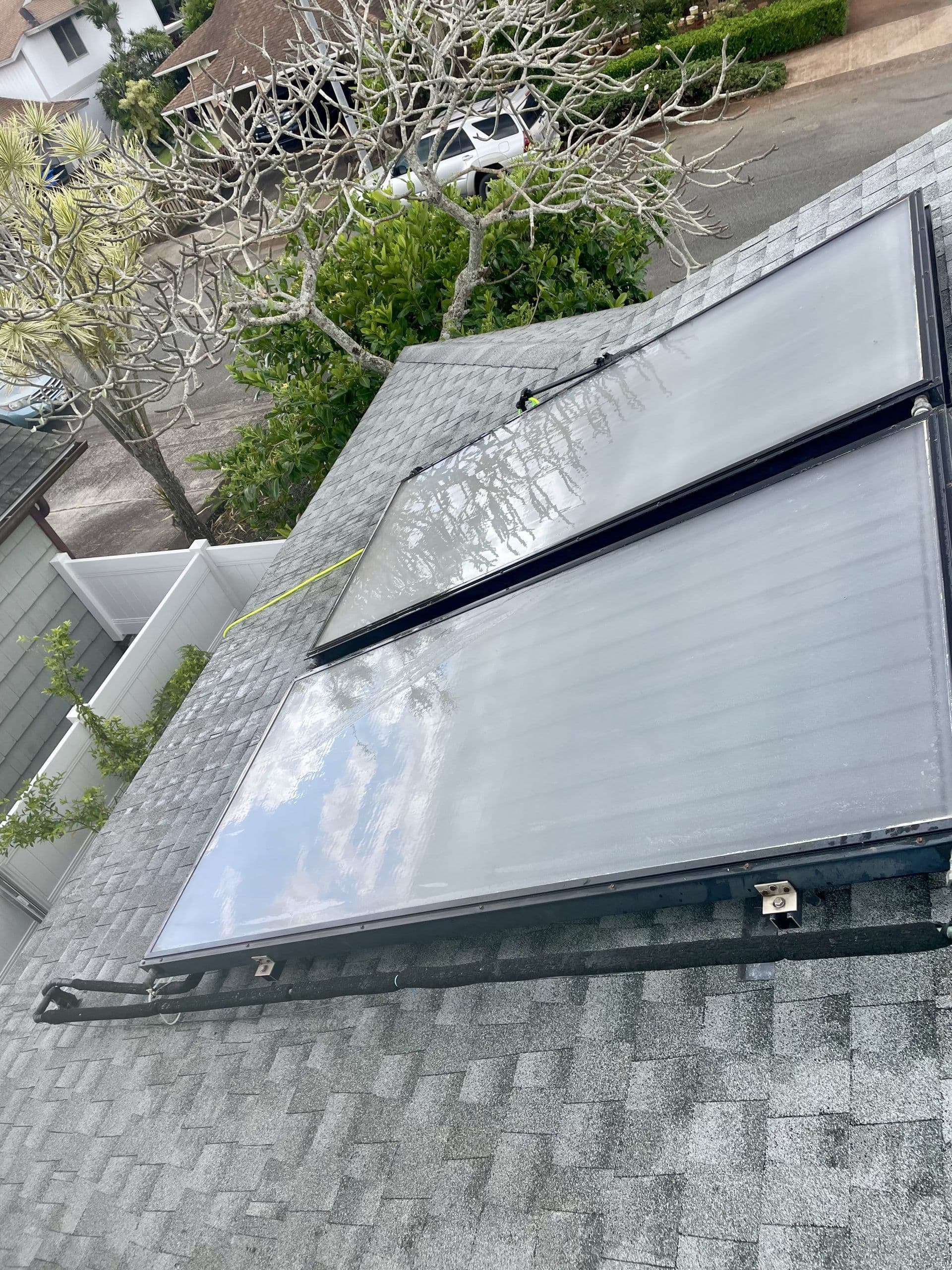 Solar panels installed on a sloped roof with trees in the background. Eco-friendly energy solution.